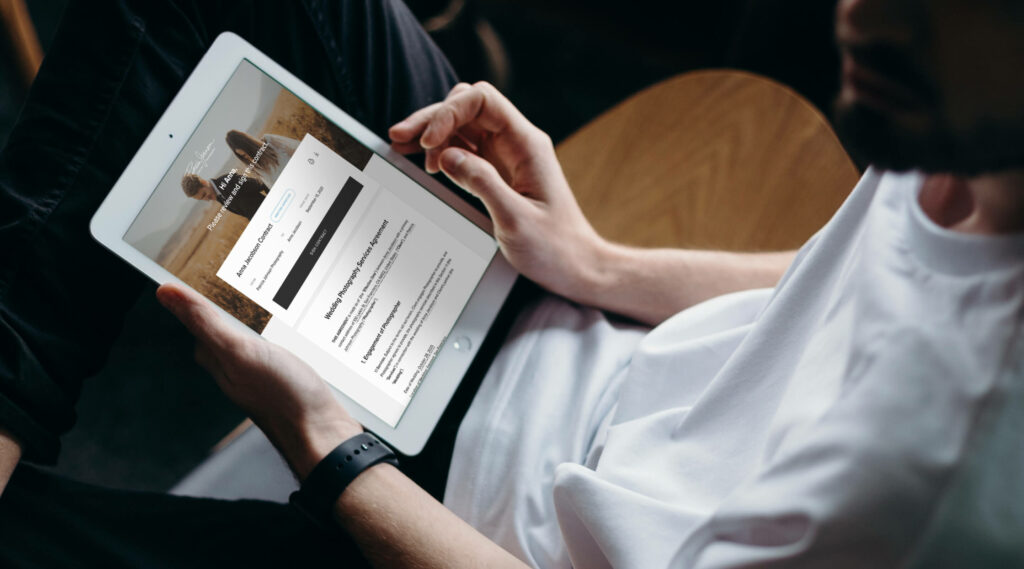 Man holding an iPad with a beautiful photography contract sent via Pixieset