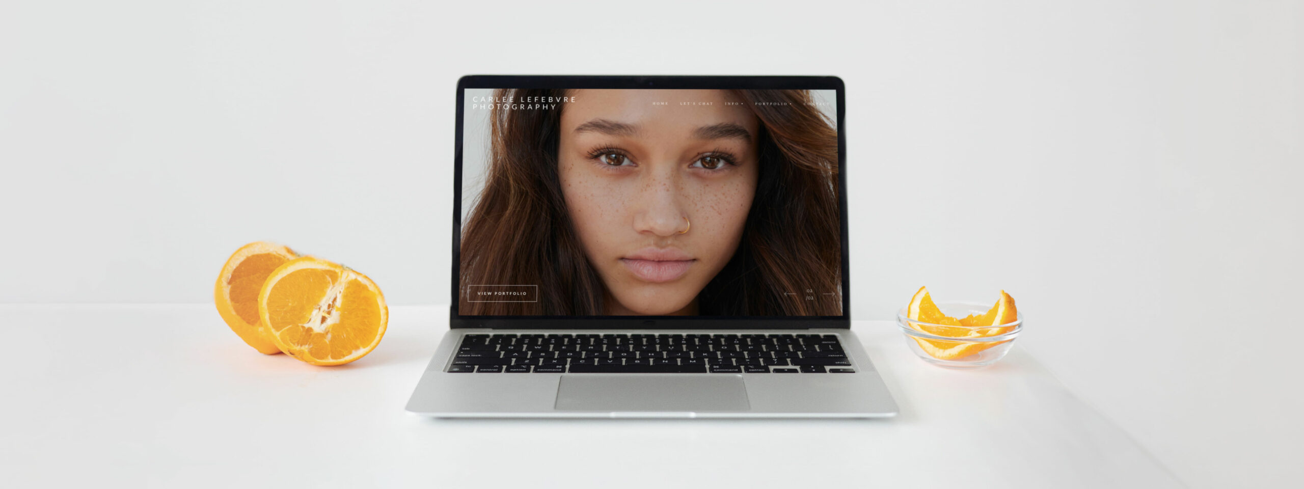 Portrait photography website viewed on a laptop alongside oranges