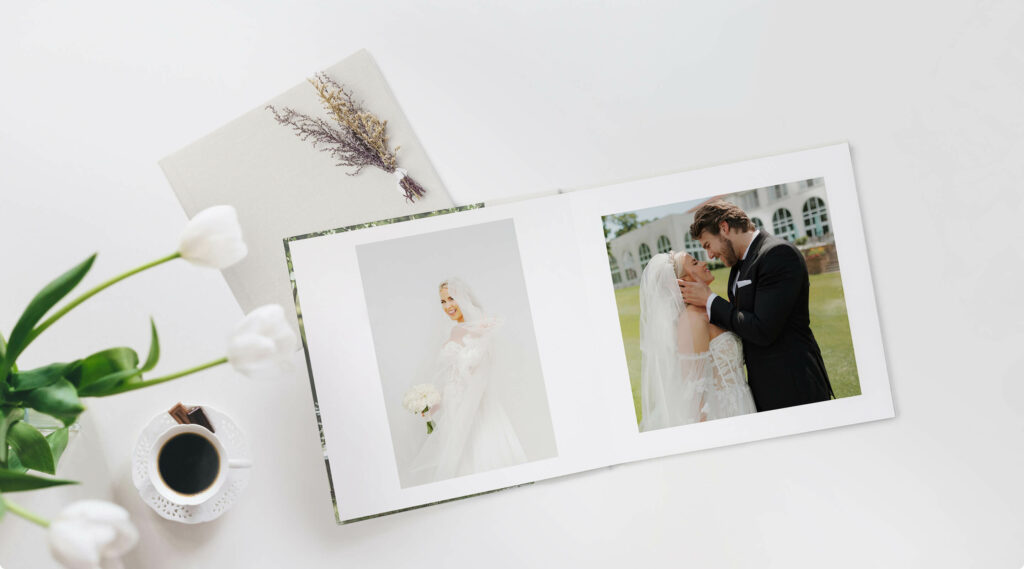 wedding photo album on a white table, opened so photos of the bride and groom are visible, with coffee and tulips visible on table. 
