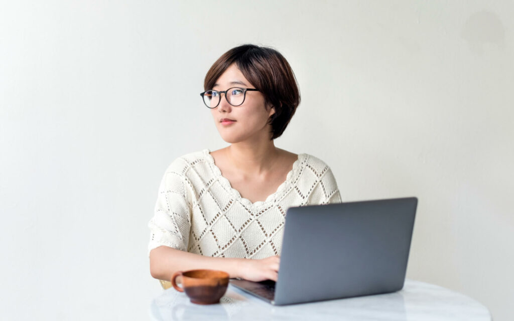A woman with glasses works at a computer.