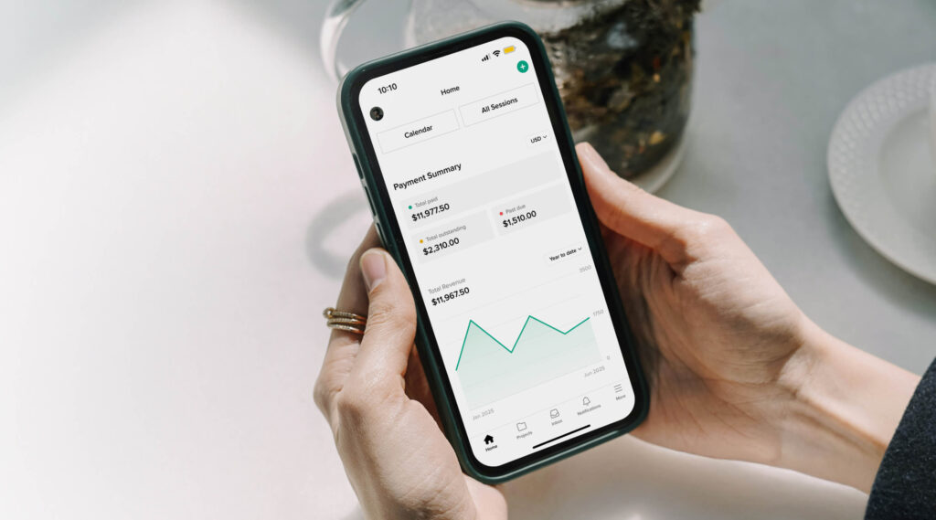 Hands holding a phone, that shows payment transactions inside Studio Manager mobile app